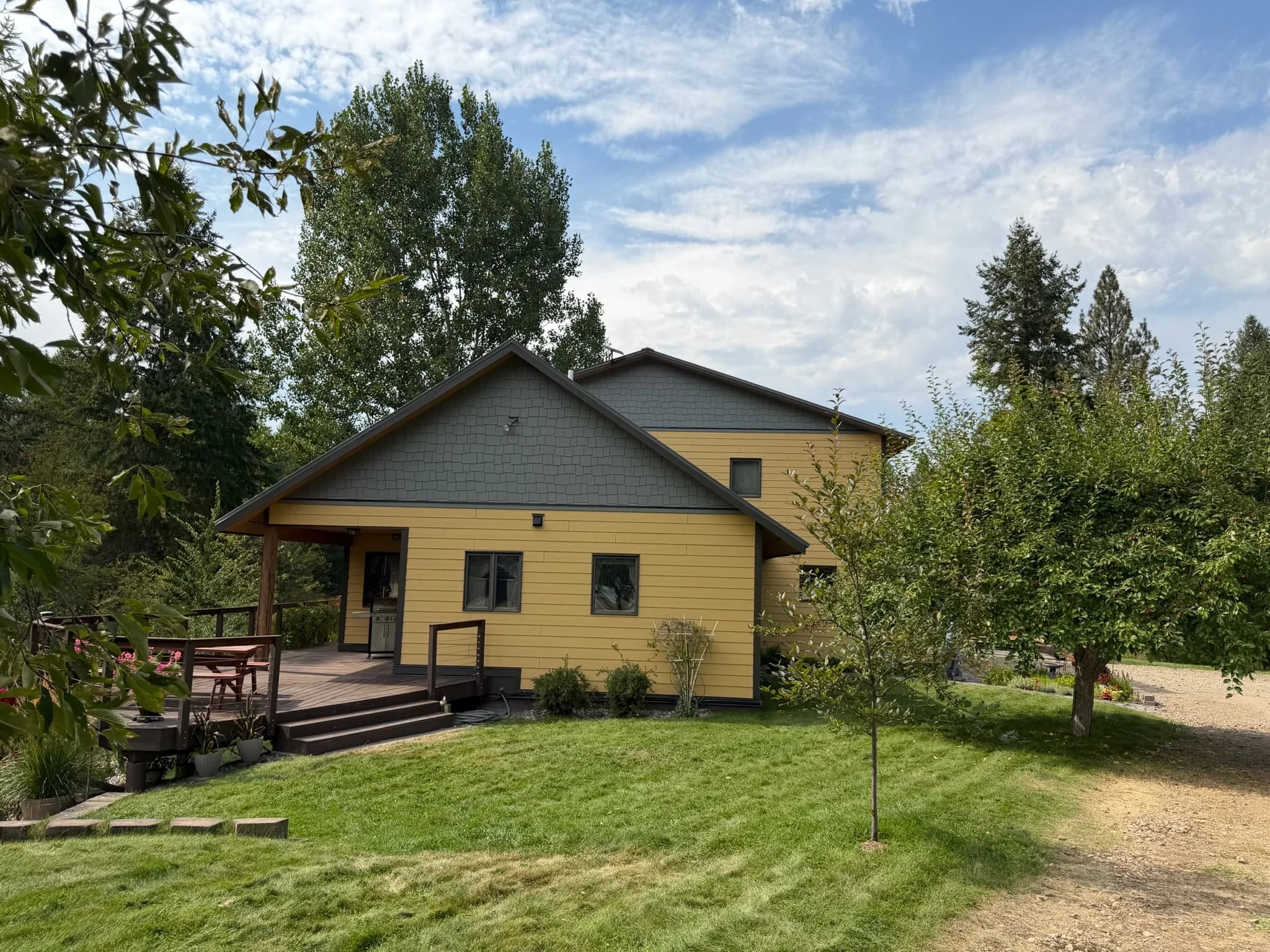 The Sunny Side Residence after the re-side: golden lap siding and a gray shake gable above the back deck